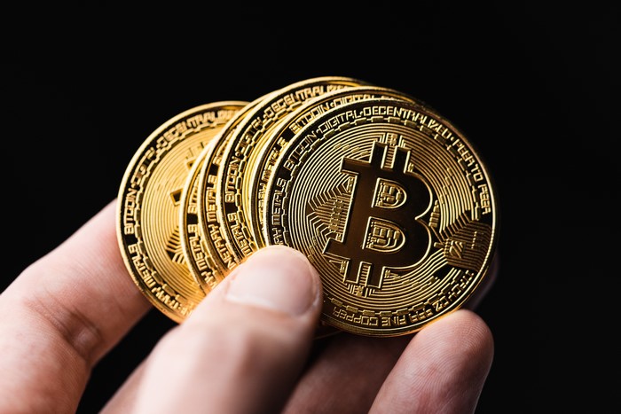 Hand holding Bitcoin coins on black background