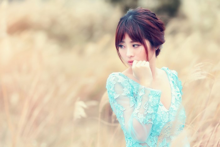 Asian woman in blue lace dress in field