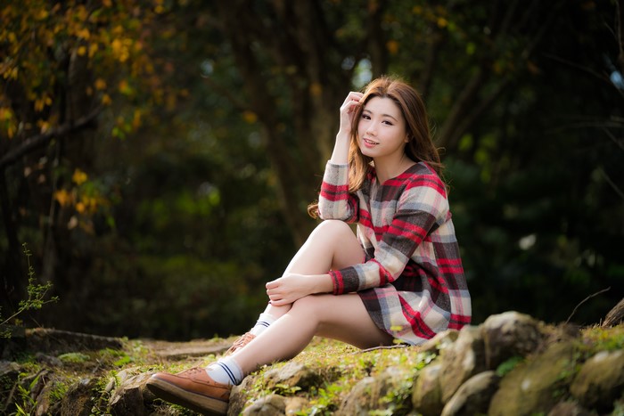 Asian woman with brown hair sitting in a forest