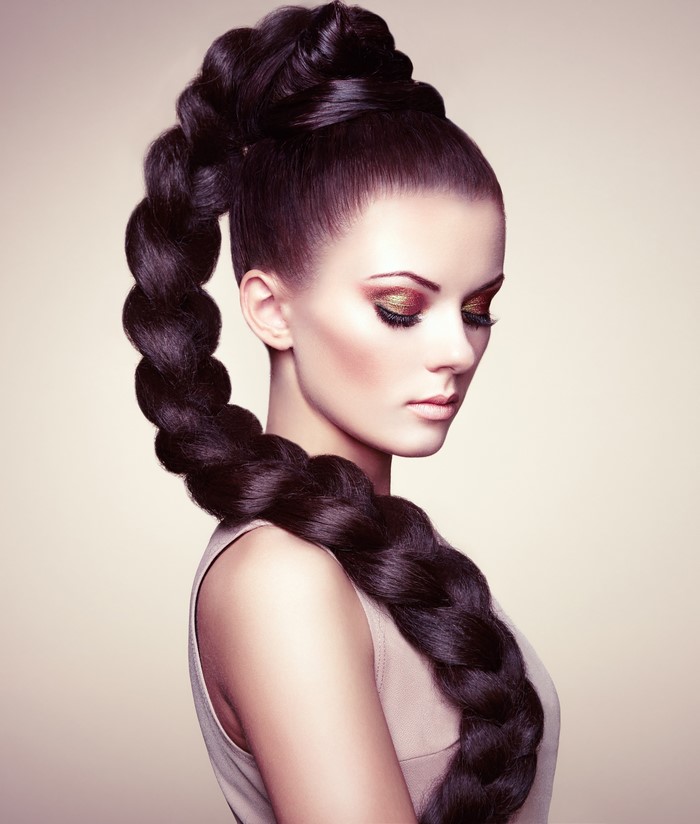 Brunette woman with elaborate braided hairstyle and makeup
