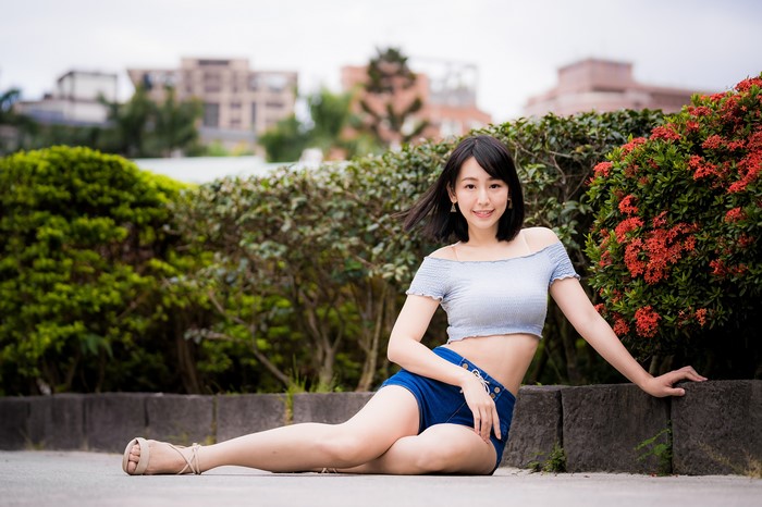 Asian woman in shorts and t-shirt sitting outdoors