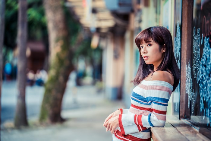 Asian woman in striped sweater looking over shoulder