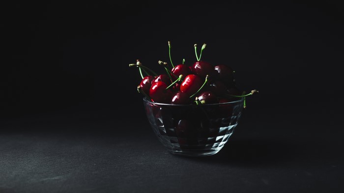 Cherries in a glass bowl on a black background