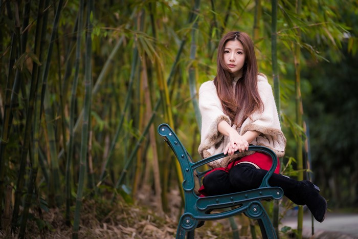 Asian woman sitting on a bench in a bamboo forest