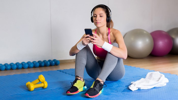 Woman with headphones and smartphone in gym