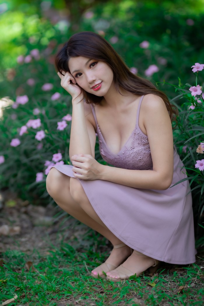 Asian woman in a purple dress crouching in a garden