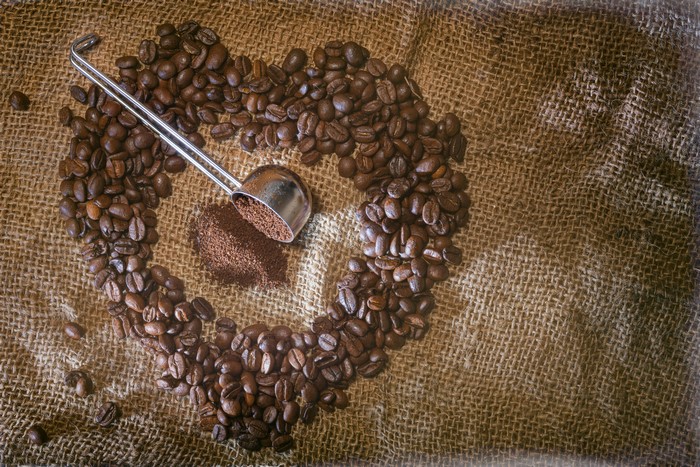 Coffee beans arranged in a heart shape with a scoop
