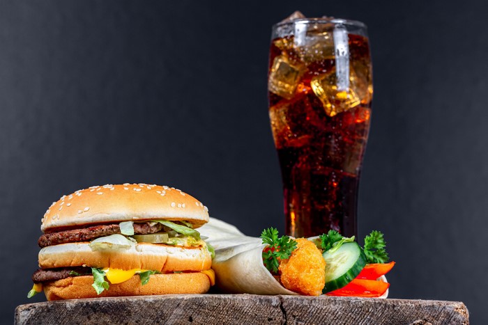 Hamburger, wrap, and Coca-Cola on a wooden surface