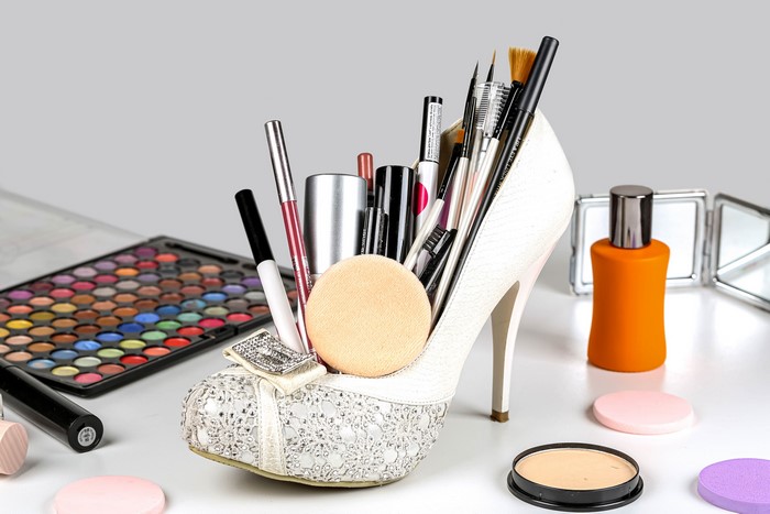 White stiletto shoe filled with makeup brushes and pencils