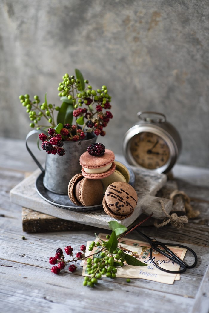 Still life with macarons, berries, and alarm clock