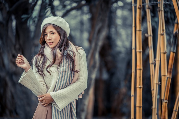Asian woman in beret and scarf with bamboo