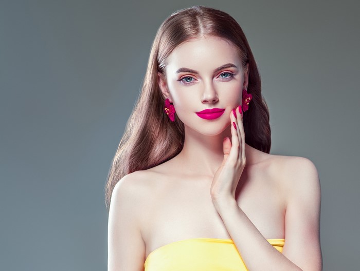 Woman with brown hair and pink earrings