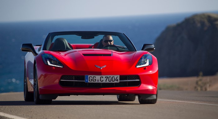 Red Chevrolet Corvette Stingray Convertible driving on a road