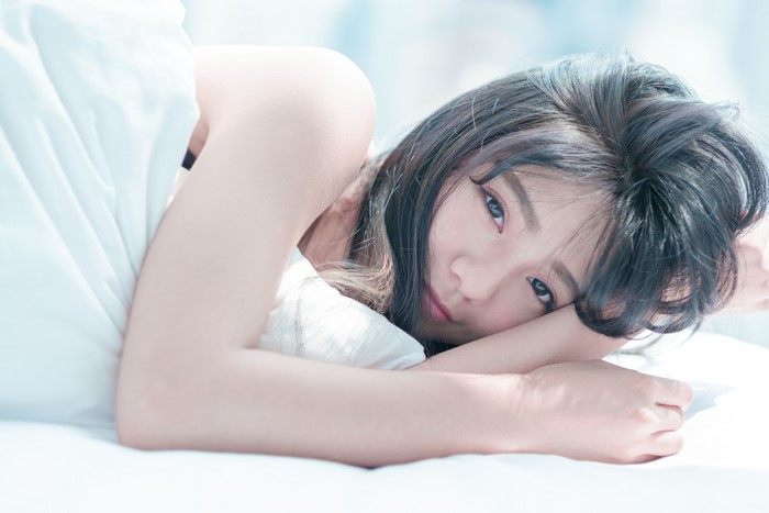 Brunette girl lying down with hands near face