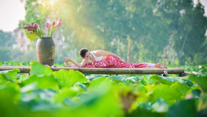 Woman doing yoga split in lotus pond