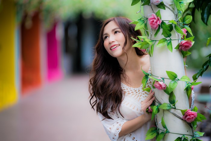 Asian woman with brown hair smiling near flowers