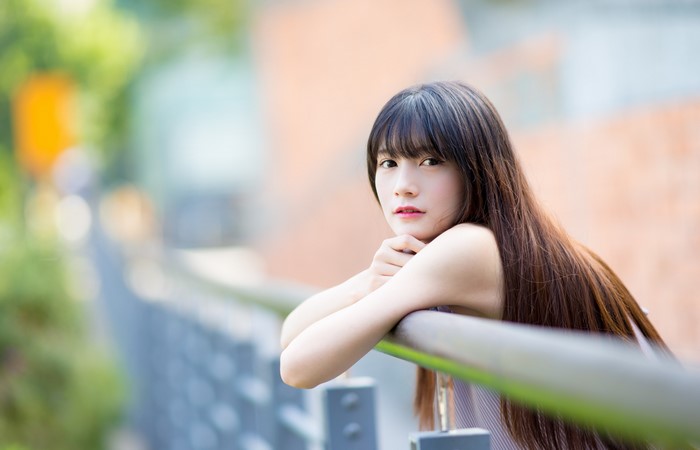 Asian Woman with Long Brown Hair Leaning on Railing