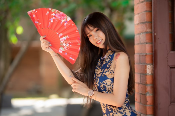 Asian woman in a dress holding a hand fan