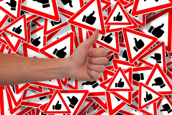 Hand giving thumbs up over like signs