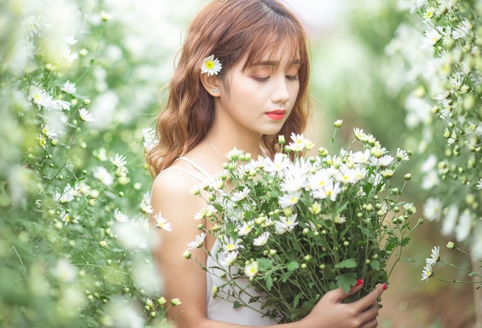 Asian girl with brown hair holding camomile bouquet