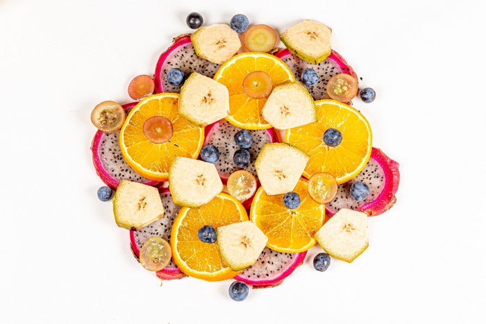 Sliced Pitaya, Bananas, Blueberries, and Orange fruit on white background