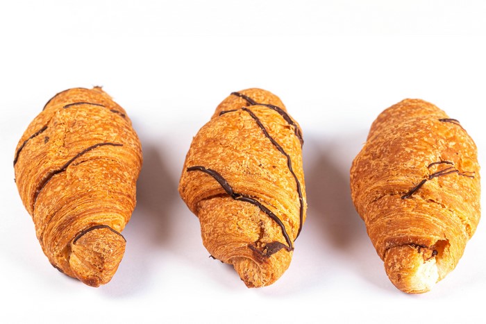 Three chocolate drizzled croissants on white background