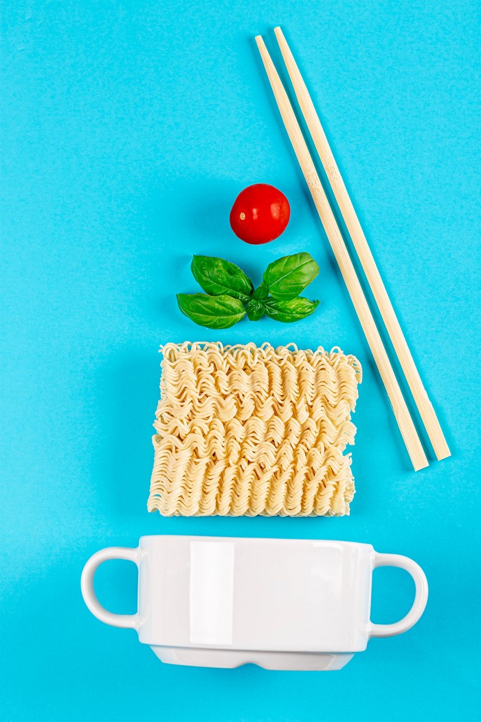 Instant noodles with tomato, basil, chopsticks, and mug