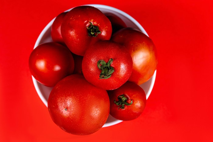 Bowl of red tomatoes on a red background