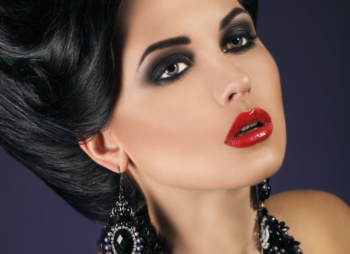 Woman with black hair, red lips, and dark makeup