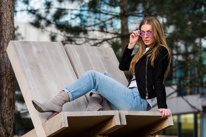 Woman wearing sunglasses and jeans sitting on a bench