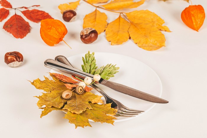 Autumn table setting with plate, cutlery, and leaves