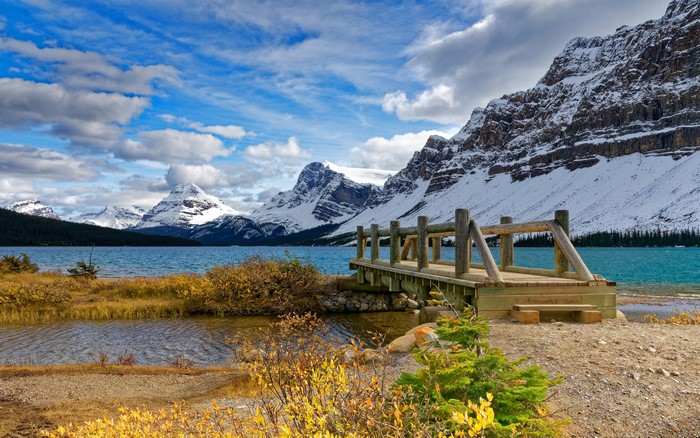 Wooden bridge over a lake with snow-capped mountains in Banff, Canada