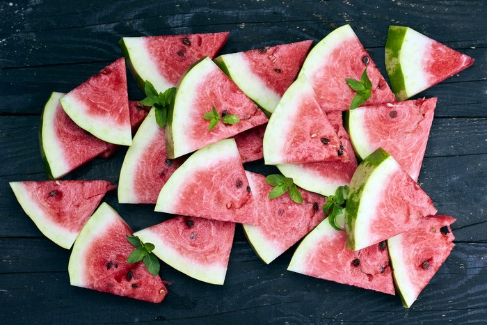 Many watermelon slices on wood planks