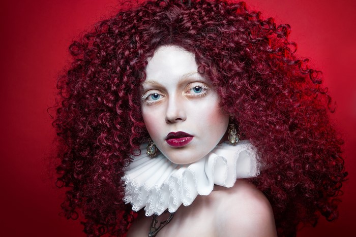 Woman with curly red hair and white makeup