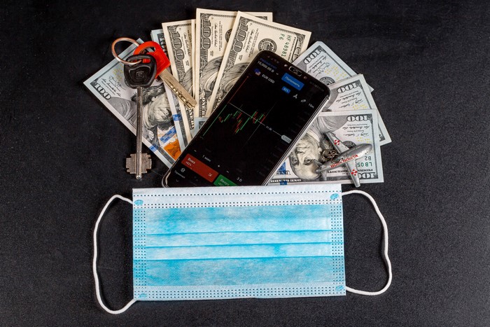 Money, Smartphone, Keys, Airplane, and Face Mask on Gray Background