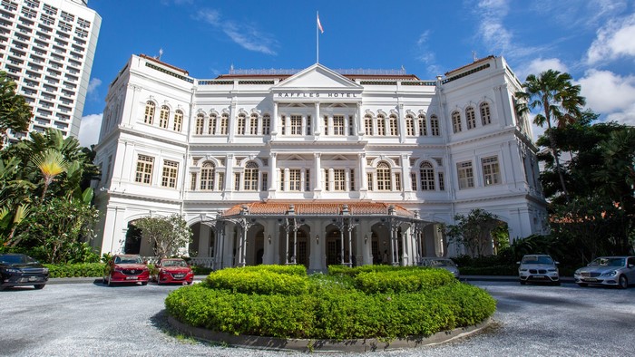 Raffles Hotel Singapore with cars and greenery