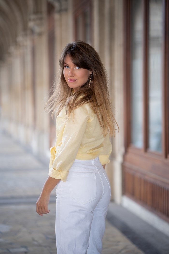 Alina wearing a yellow shirt and white trousers