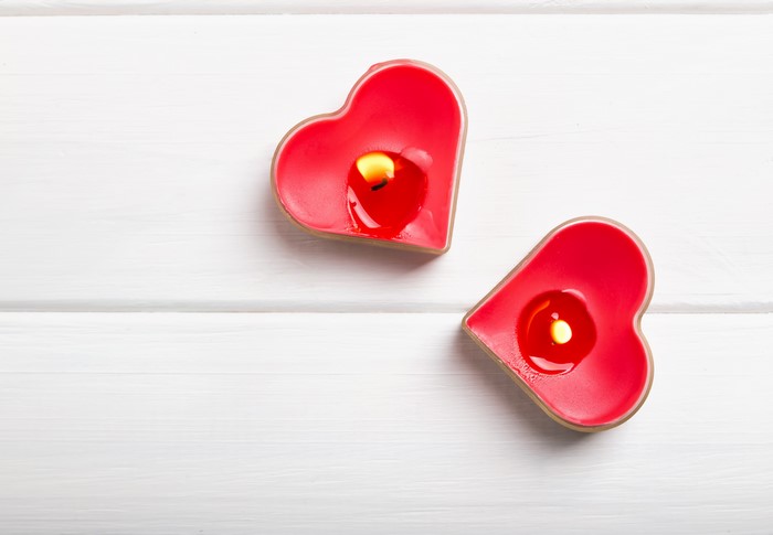 Two red heart-shaped candles burning