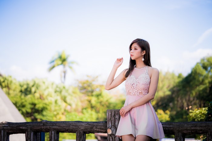 Asian woman in pink dress posing outdoors