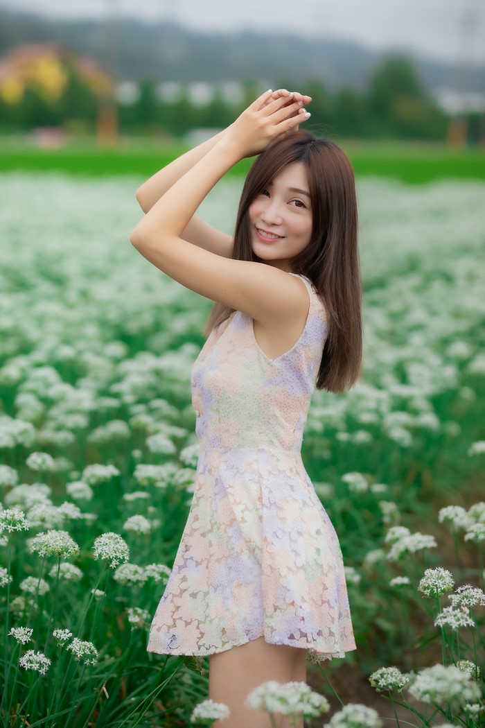 Asian woman in a floral dress in a field of white flowers