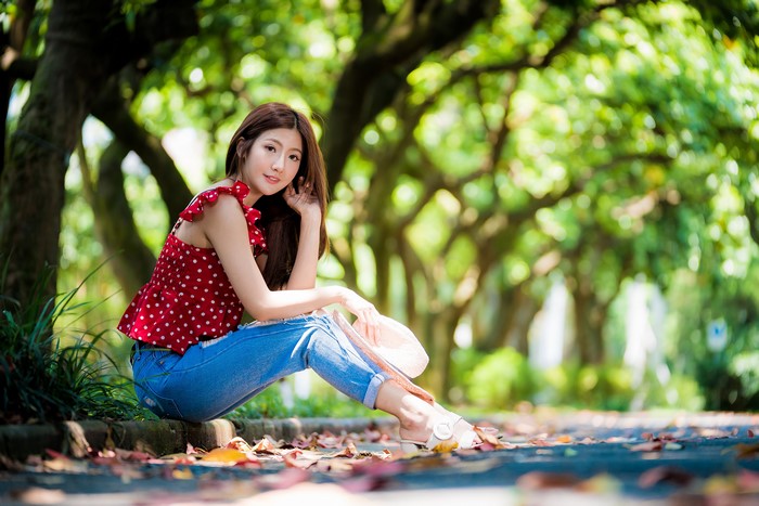 Asian woman sitting in a park with jeans and blouse