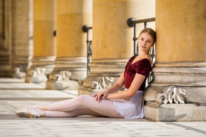 Valerie sitting in ballet attire by columns