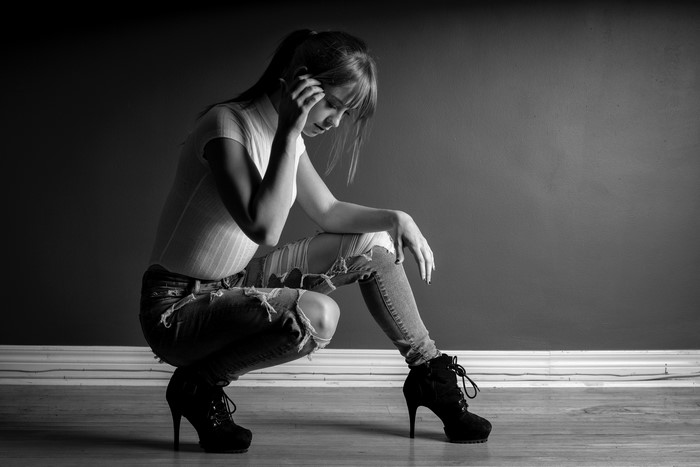 Woman in ripped jeans and stilettos crouching