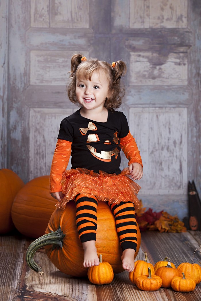 Girl in Halloween Costume Sitting on Pumpkin