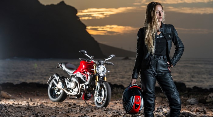 Woman in leather with Ducati motorcycle at sunset