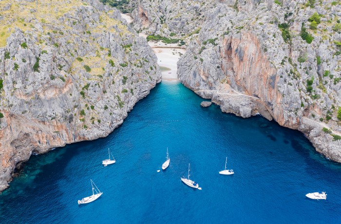 Sailboats in a bay between rocky cliffs in Mallorca
