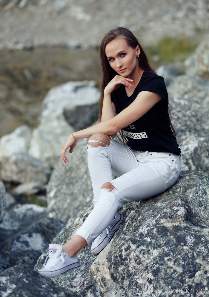 Nastya sitting on rocks wearing ripped jeans and t-shirt