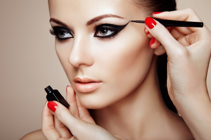 Woman applying eyeliner with red manicure