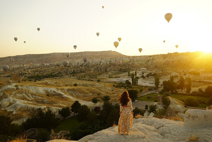 Woman in dress watching hot air balloons in Cappadocia at sunset
