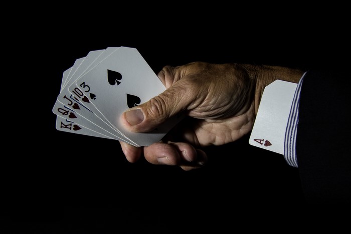Hand holding playing cards with Ace in sleeve